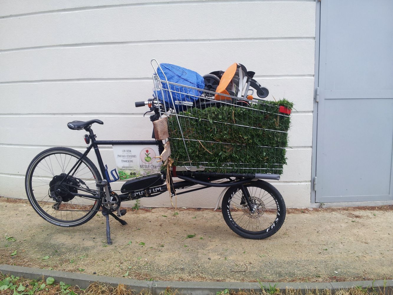 vélo cargo transportant une tondeuse manuelle et de la tonte de gazon