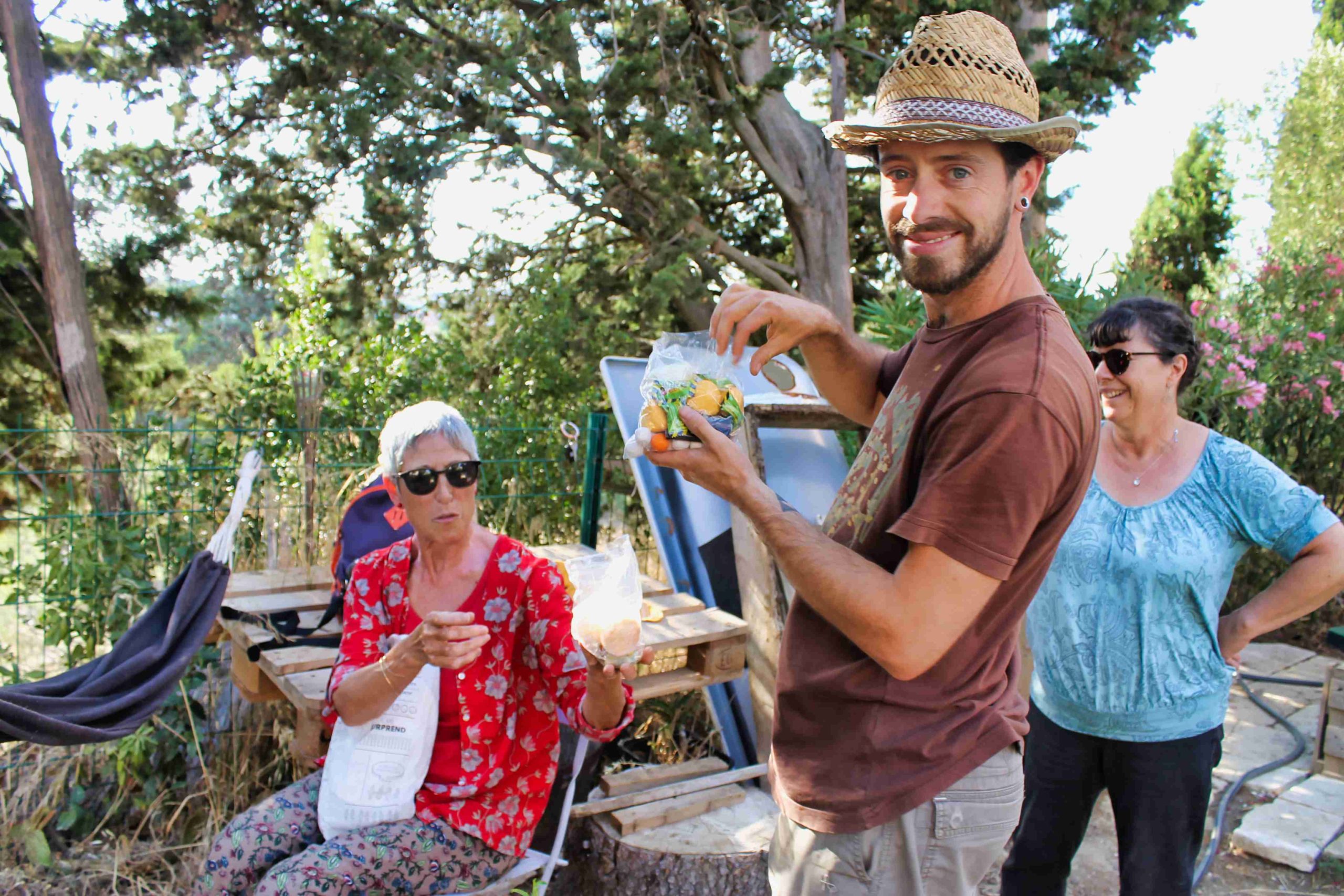 des gens partageant un repas dans un jardin partagée en été, sous un beau soleil de fin d'après-midi