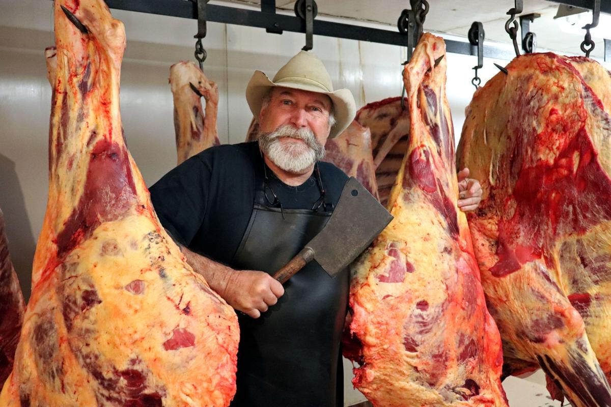 boucher avec un fendoir à côté de pièce de viande