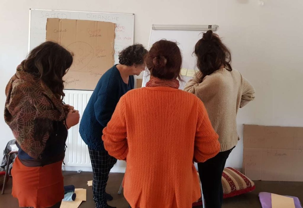 quatres personnes travaillent sur un paperboard pendant un exercice lors d'une formation sur la gouvernance partagée et l'intelligence collective